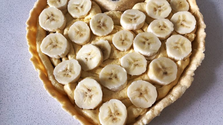 香蕉莓果塔,香蕉均勻的碼放在奶油餡上面，可以輕輕的往下按一按