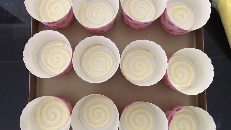 棒棒糖蛋糕,先将装有原色的裱花袋剪小口，在纸杯底画出螺旋状，如图，画好12个。