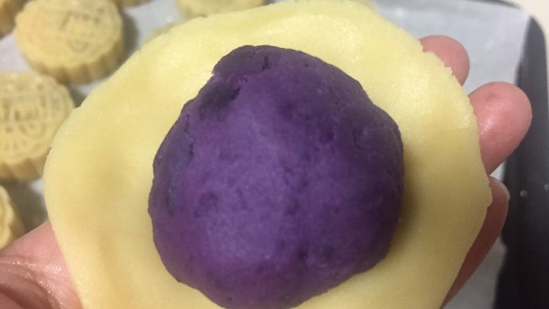 广式月饼（紫薯蛋黄馅）,醒好的月饼皮面团称重分成40克一个的小剂子，取一个小剂子捏成圆片紫薯蛋黄放在面皮中间
