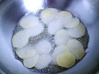 椒盐炸薯片,一片一片快速把土豆片放入油锅中。（一定要一片一片的快速放入，千万不要全部倒入，不然会粘到一起！）