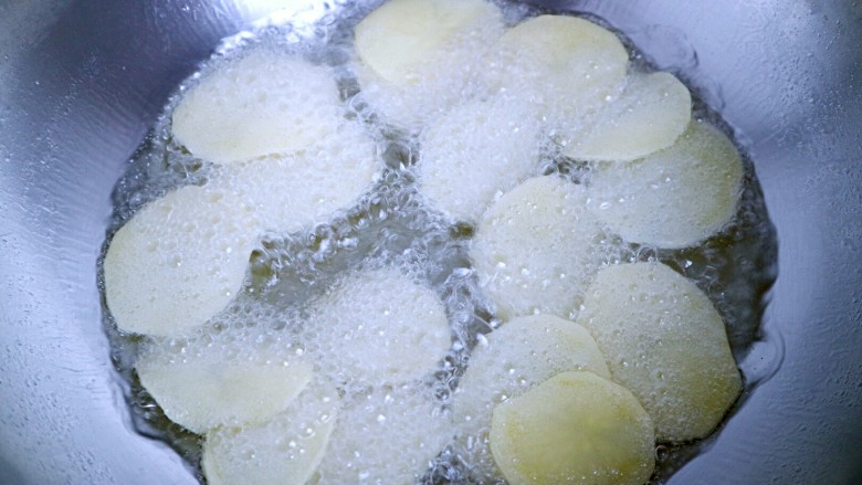 椒盐炸薯片,一片一片快速把土豆片放入油锅中。（一定要一片一片的快速放入，千万不要全部倒入，不然会粘到一起！）