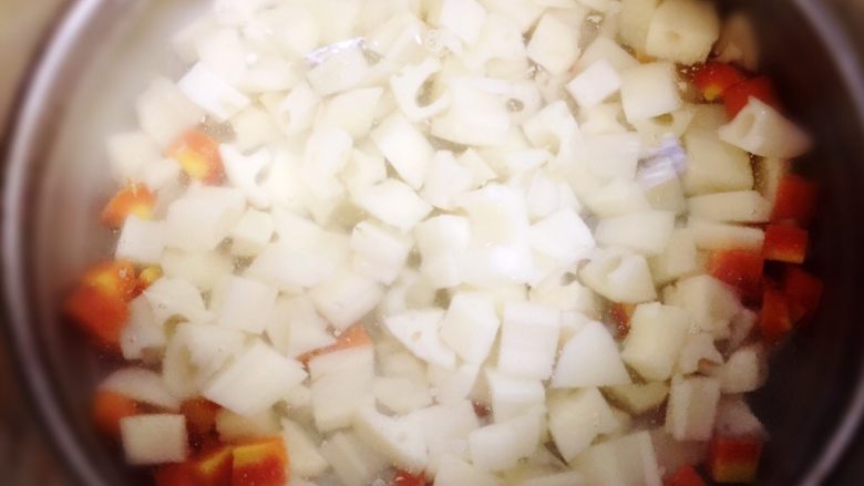 酸辣藕丁,锅里水烧开后，放入胡萝卜煮半分钟。再放入藕丁一起焯水一分钟左右。