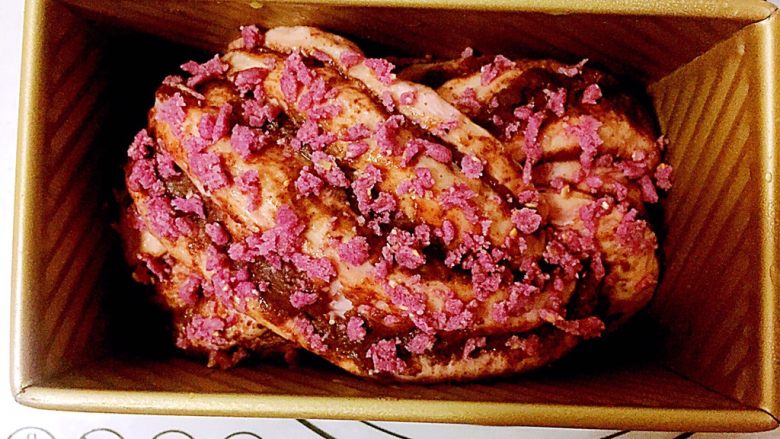 紫薯奶酥粒豆沙吐司,吐司盒从烤箱中取出，烤箱预热180度，吐司刷薄蛋液将<a style='color:red;display:inline-block;' href='/shicai/ 2643'>紫薯</a>奶酥粒均匀的撒在面团上。