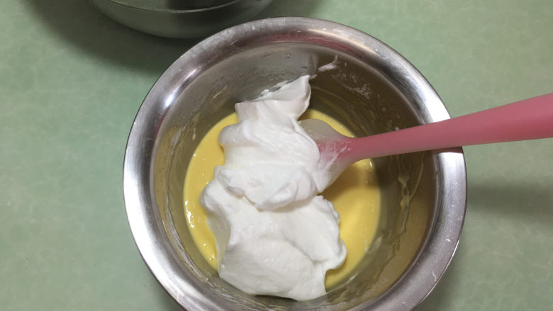 形彩绘芒果蛋糕卷,取三分之一蛋白加入蛋黄糊中。（这个时候可以进行烤箱预热，温度为180度。）