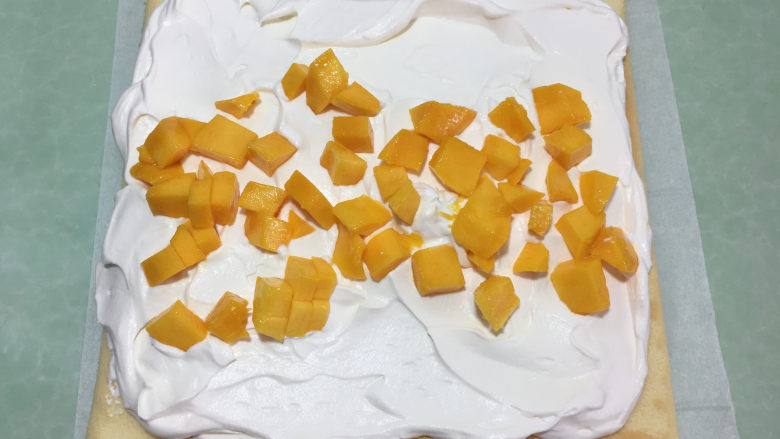 形彩绘芒果蛋糕卷,蛋糕晾凉后在没有花纹的一面上涂抹上奶油，中间铺上芒果丁。