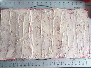 覆盆子红丝绒蛋糕,将覆盆子玫瑰奶油均匀的涂抹在长方形蛋糕片