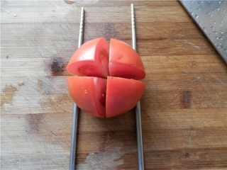 莲花番茄,将一个番茄洗净竖起来，旁边放二根筷子，先横竖各切一刀。