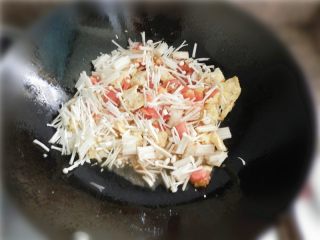 莲花番茄,倒入番茄肉和姜片，倒入金针菇，一起翻炒。