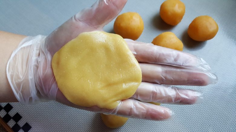 广式月饼~金沙奶黄馅儿,14．取一个月饼皮，在手心按成圆形的皮，大小以能包的住馅料为准。