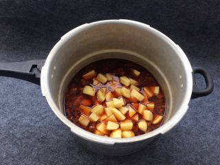 土豆炖牛腩,等高压锅气阀下之后，打开锅盖，土豆倒入牛肉中。