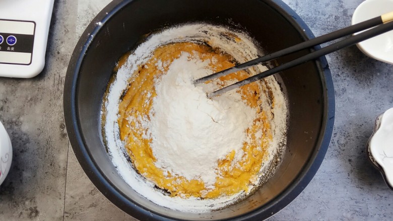 奶香小星星南瓜馒头,慢慢倒入面粉，一边到一边用筷子进行搅拌，直到呈柳絮状