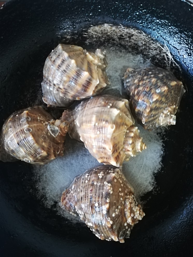 葱爆海螺,把洗净的海螺倒扣入炒菜勺里