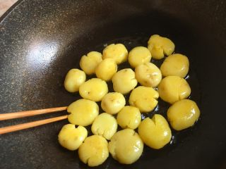 孜然小土豆,一面煎至金黄色后用筷子翻面，继续煎，煎至两面金黄后夹出备用