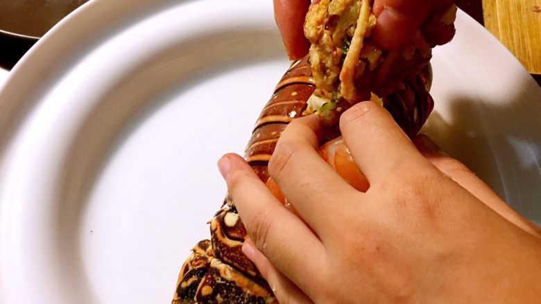 烤澳州龙虾尾配海鲜馅料,将起锅的海鲜馅料塞入虾尾壳，然后再最上面虾背盖上一张芝士片。