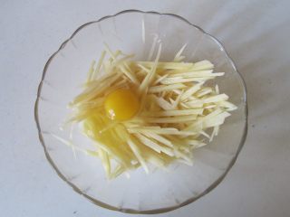 土豆丝饼,土豆切成丝放入碗中， 打入鸡蛋；