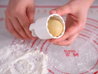 【烘焙配方】经典广式月饼,手上粘少许粉，将包好月饼馅的饼胚放手上稍微搓一下，饼胚放入月饼模具里