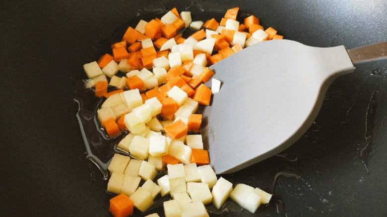 咖喱鱼丸,锅中倒入适量食用油烧热，放入胡萝卜丁和土豆丁翻炒均匀。