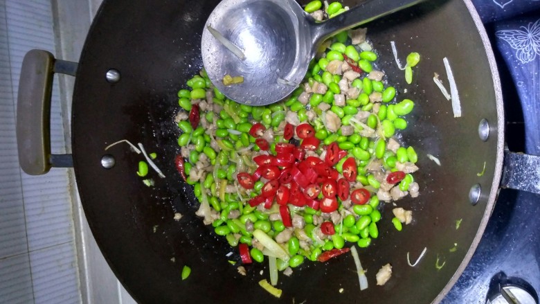 毛豆辣椒炒肉,放入毛豆，红辣椒圈，翻炒均匀，加入少许盐调味。