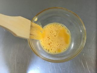广式蛋黄豆沙月饼,蛋黄打散，刷蛋液之前，毛刷沾了蛋液后，最好在碗口上把多余的蛋液刮掉，再去刷月饼，这样刷出来的蛋液清晰不糊