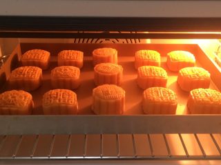 广式莲蓉蛋黄月饼,全部刷好，放入烤箱中层，上下170度烤14分钟，表面喷一点点水 ，防止开裂。时间和温度要根据各自烤箱脾气设置哈，月饼大小个时间也不一样的。
