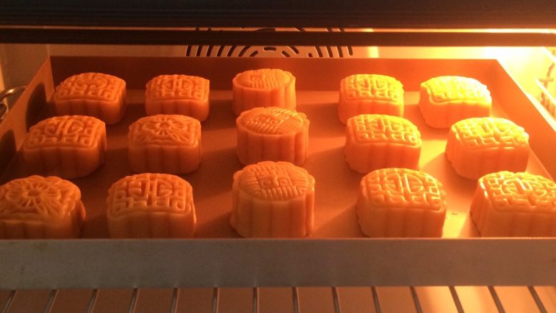 广式莲蓉蛋黄月饼,全部刷好，放入烤箱中层，上下170度烤14分钟，表面喷一点点水 ，防止开裂。时间和温度要根据各自烤箱脾气设置哈，月饼大小个时间也不一样的。