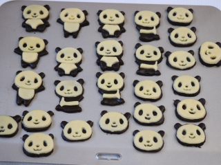 熊猫饼干,用同样的方式将原色面团擀成薄皮后用模具按压出脸部外形、表情部分、腹部部分，然后依次摆在可可面团的熊猫形状上；