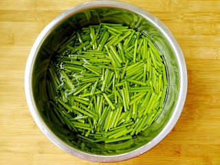 韭菜苔炒香干,把切好的韭菜苔放入装有清水的盆中，泡十分钟。