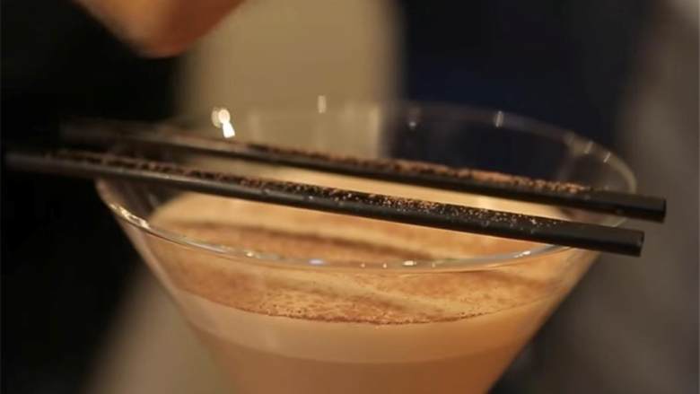 冰咖啡鸡尾酒,在酒杯杯口上放两根短吸管，平行放置，然后筛上可可粉，做出花纹。