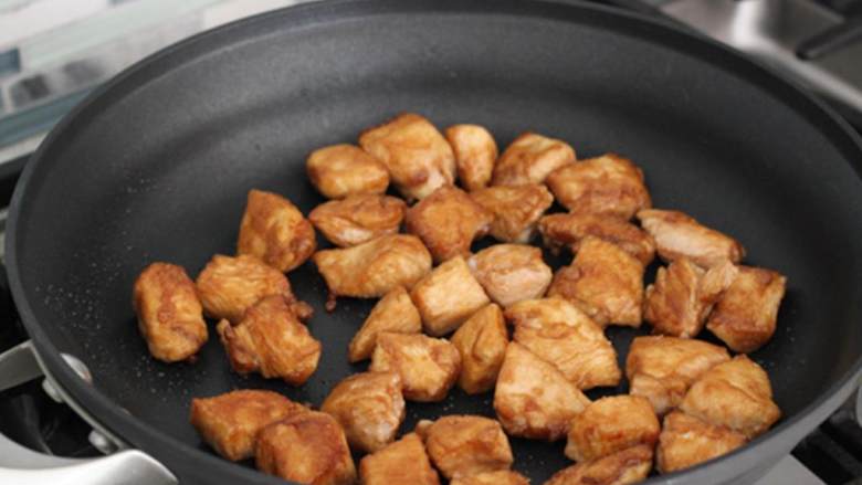 甜酸鸡,取一个30厘米的平底不粘锅，中火加热芥花油，分两批煎鸡肉，每面煎2-3分钟。