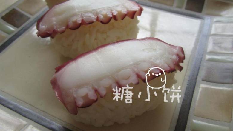章鱼片握寿司,抹芥末膏的一面朝下，将章鱼切片覆盖在饭团上。芥末膏既杀菌调味，也起到了粘合饭团和顶料的作用.