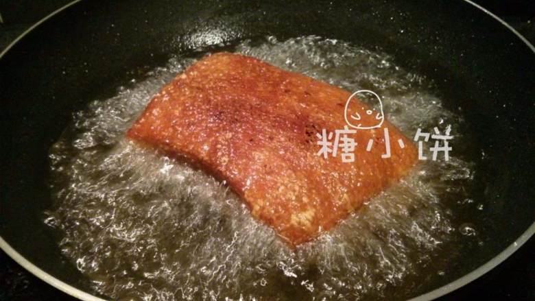 梅干菜扣肉（传统油炸版）,盖上锅盖（这是为了防止被油爆到）炸至表皮金黄起泡后再翻面炸一会儿，至四周都上色的程度。