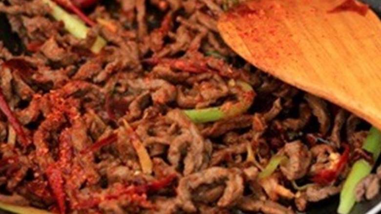 干煸牛肉丝,撒上辣椒面 、花椒面 和芝麻 ，快速翻炒使所有食材均匀混合。