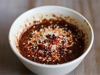 辣椒油,在碗中加入2汤匙辣椒面 、炒熟的白芝麻 和花椒面 。