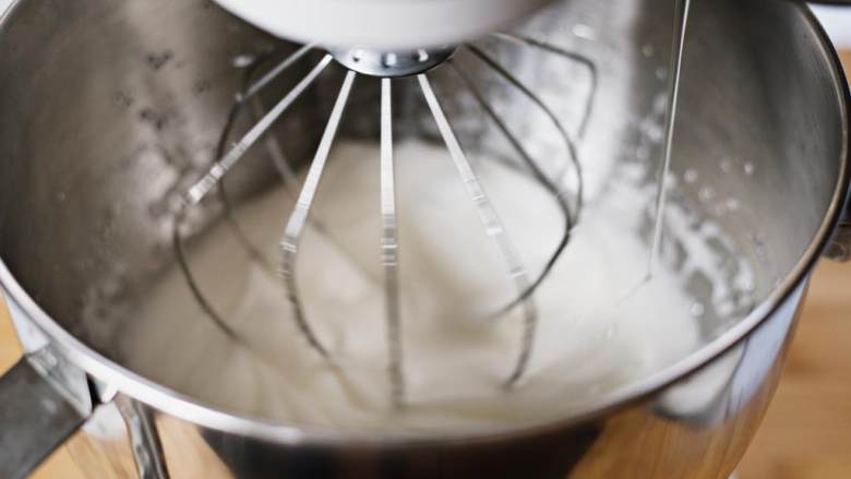 免烤蛋白夹心派,搅拌器保持中速，慢慢加入糖水。