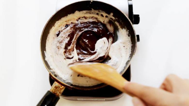 冰皮巧克力流心月饼,稍稍冷却片刻后加入纯可可脂黑巧克力 ，迅速搅拌均匀。加入巧克力时温度不宜太高，不然会油水分离。