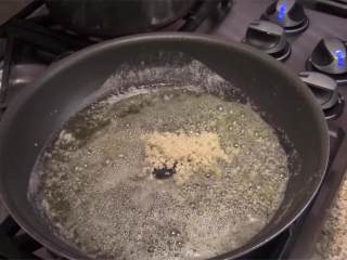鲜虾意面,中火加热平底锅，加入橄榄油和黄油 。黄油开始冒泡后加入大蒜，煎1分钟。