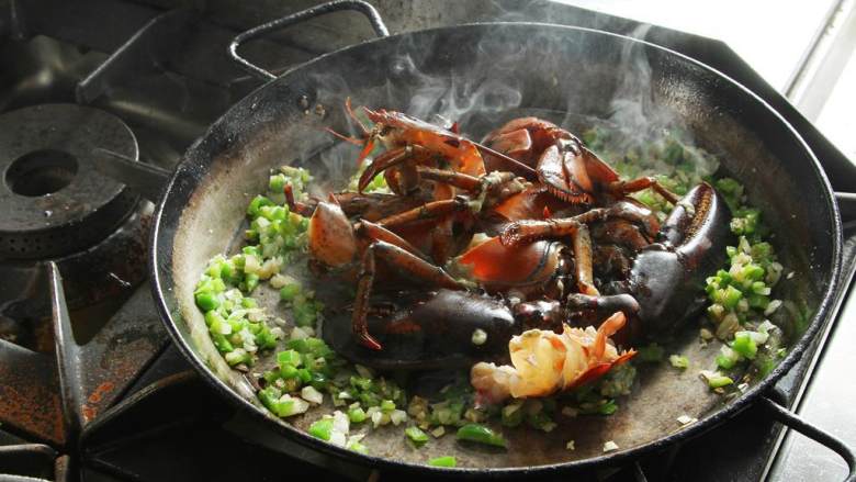 波士顿龙虾海鲜饭,加入龙虾，煮至出水。龙虾变色后，舀出，但是龙虾头还是留在锅里。