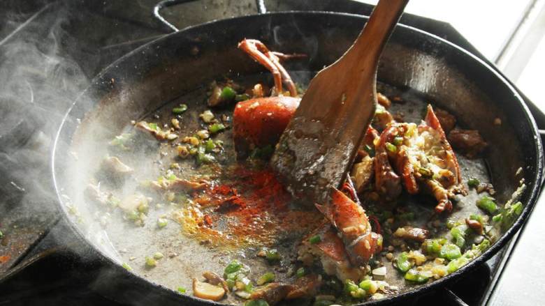波士顿龙虾海鲜饭,食材都聚拢在锅中心，加入橄榄油 和烟熏辣椒粉(5 克)，煮几秒钟。