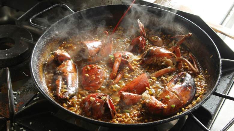 波士顿龙虾海鲜饭,把龙虾转移到海鲜饭专用锅中。在快烧干的时候，加入一些龙虾高汤。然后放入180度的烤箱里烤5分钟，注意不要把米烤烂，它需要有嚼劲，硬硬的。