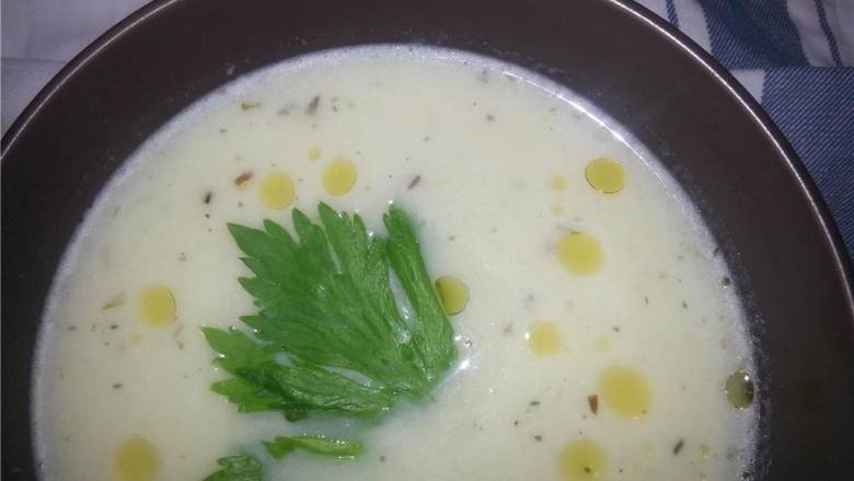 韭葱土豆奶油汤,将搅拌好的汤倒入碗中，放上一片绿叶子做装饰，我用的是芹菜叶。再滴上几滴橄榄油，就可以吃了！
