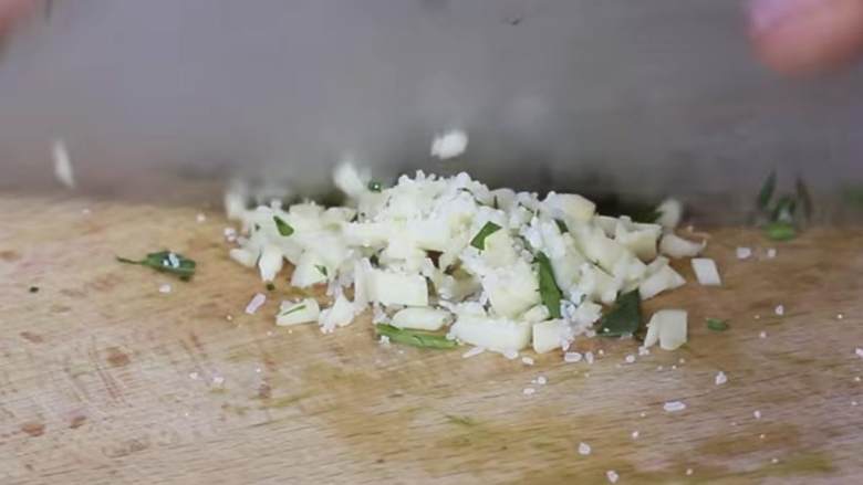 苹果鳄梨鸡肉色拉,将蒜香(1) 和盐一起切碎加入搅拌机中。盐使蒜香面团制作起来更好。用刀刮下并剁碎，完成面团的制作。