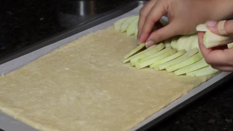 苹果酱馅饼,任意重叠地将苹果片覆盖在面包上，直到完全覆盖满苹果片，直到边缘，因为苹果将在炉收缩。
