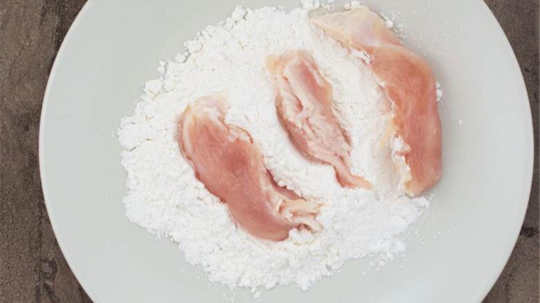 烤鸡肉卷,将鸡胸片过上面粉，用掌心压。这个会帮助鸡胸肉煎均匀。