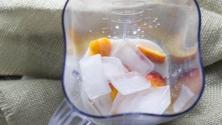 桃子燕麦冰沙,将桃子、未加工燕麦片、蜂蜜、杏仁奶 和冰块 倒进搅拌器。