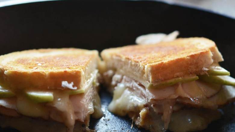 苹果火鸡三明治,芝士融化后，面包烤好后，将三明治切成一半。