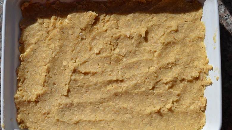 覆盆子燕麦条,把面团分成两份，将其中一份平整地压进烤盘覆盖住底部。