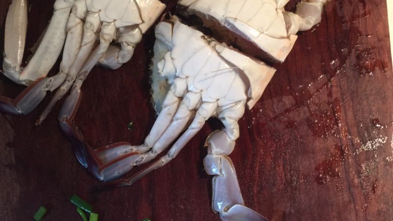 家烧梭子蟹,先不要剪断皮筋，以防切的时候被钳子夹到手，把螃蟹肚皮朝上，然后用刀从中间对半切开，然后再剪断大钳子上的皮筋