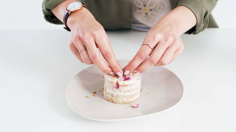 迷你玫瑰蛋糕,小心将蛋糕从甜点圈中取出，如有需要，可用小刀辅助松动。将剩余的奶油抹到每块蛋糕的顶上，如果喜欢，也可以抹在蛋糕边缘。饰以玫瑰花瓣干。