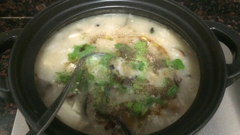 小米海鲜营养粥,撒上芹叶碎、胡椒粉，勺子拌匀。