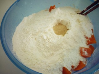 南瓜猪肉豇豆包子,放入300克面粉，用筷子搅个坑倒入酵母，用牛奶倒入坑里。